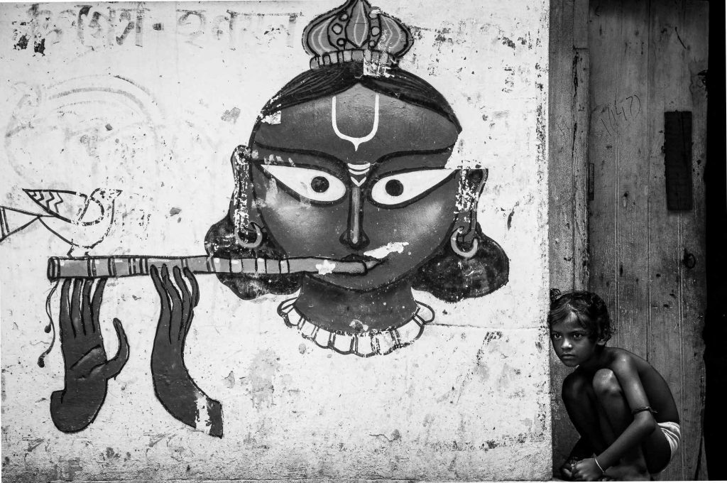 A kid is seen as she poses in front of a wall mural in the streets of Kumartuli, Kolkata