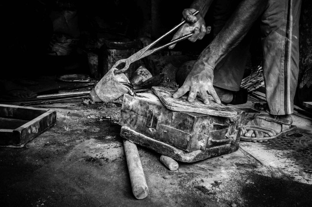 Worker pouring molten alloy into the mold