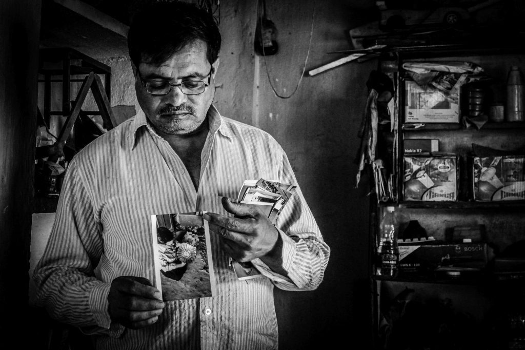 An artisan showing his photos while making the Bidriware