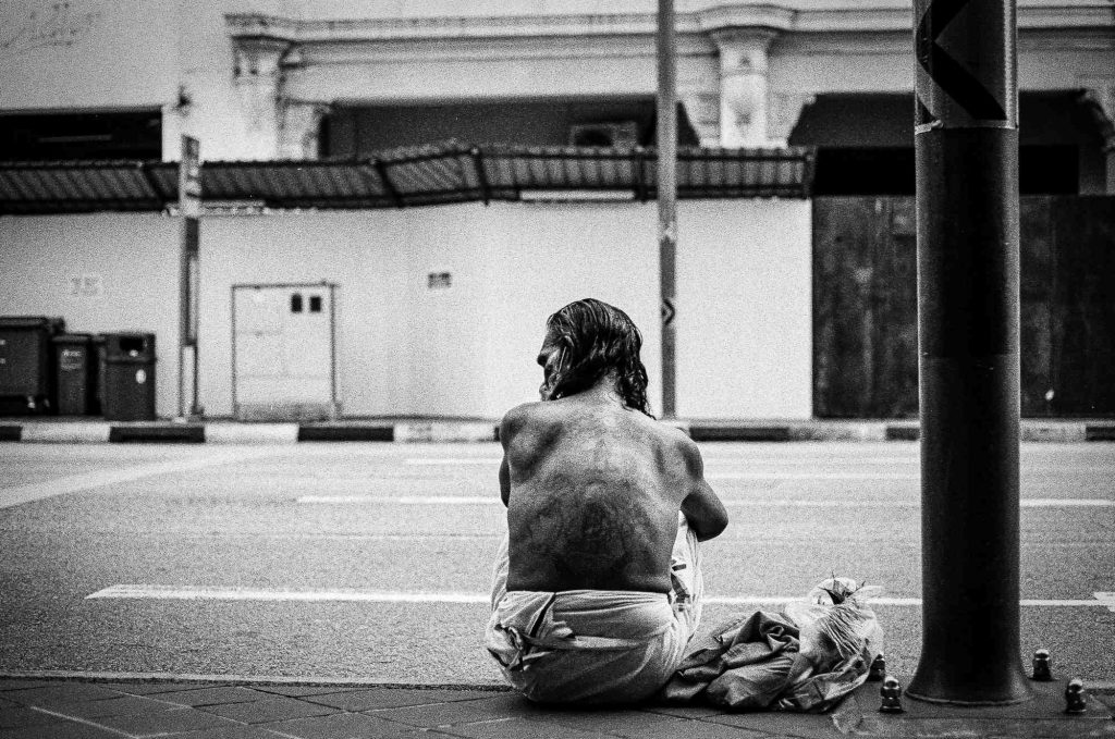 A middle-aged man waits outside the Sri Mariamman Temple, Chinatown, Singapore