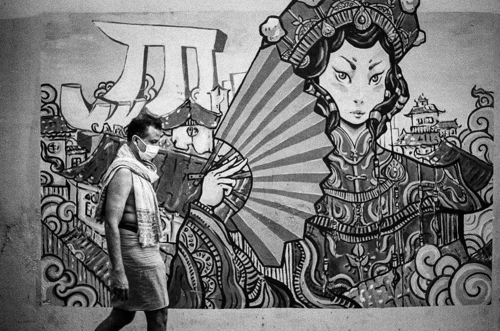 A Hindu devotee wearing a surgical mask is seen as he passes by the wall graffiti in Chinatown, Singapore.