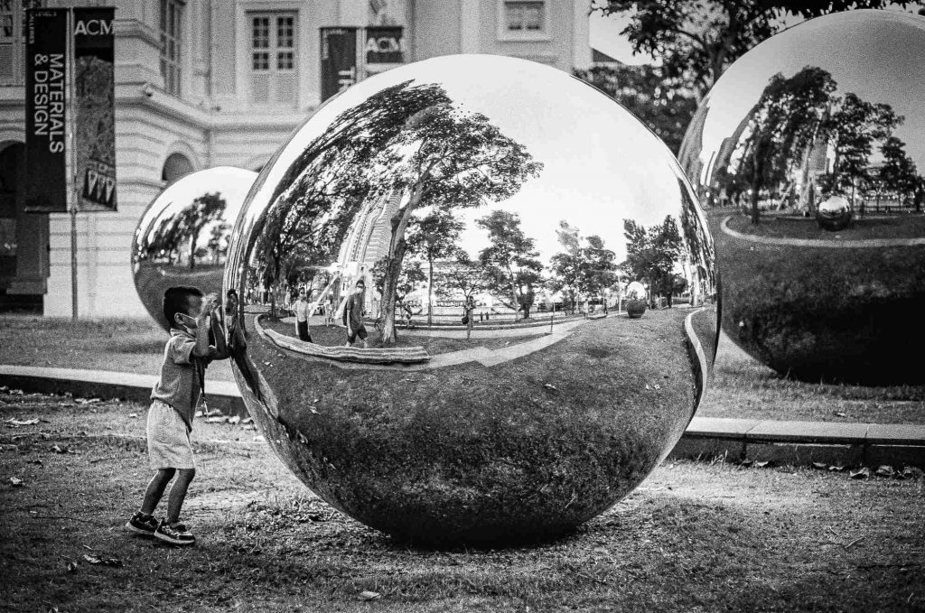 A kid is seen as he plays with the giant reflective globes in front of Asian Civilisations Museum, Singapore