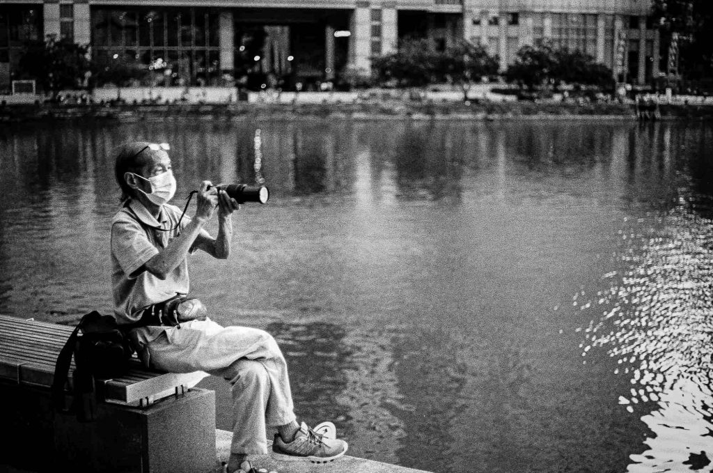 An old man is seen as he takes photos in the Promenade area in Singapore.
