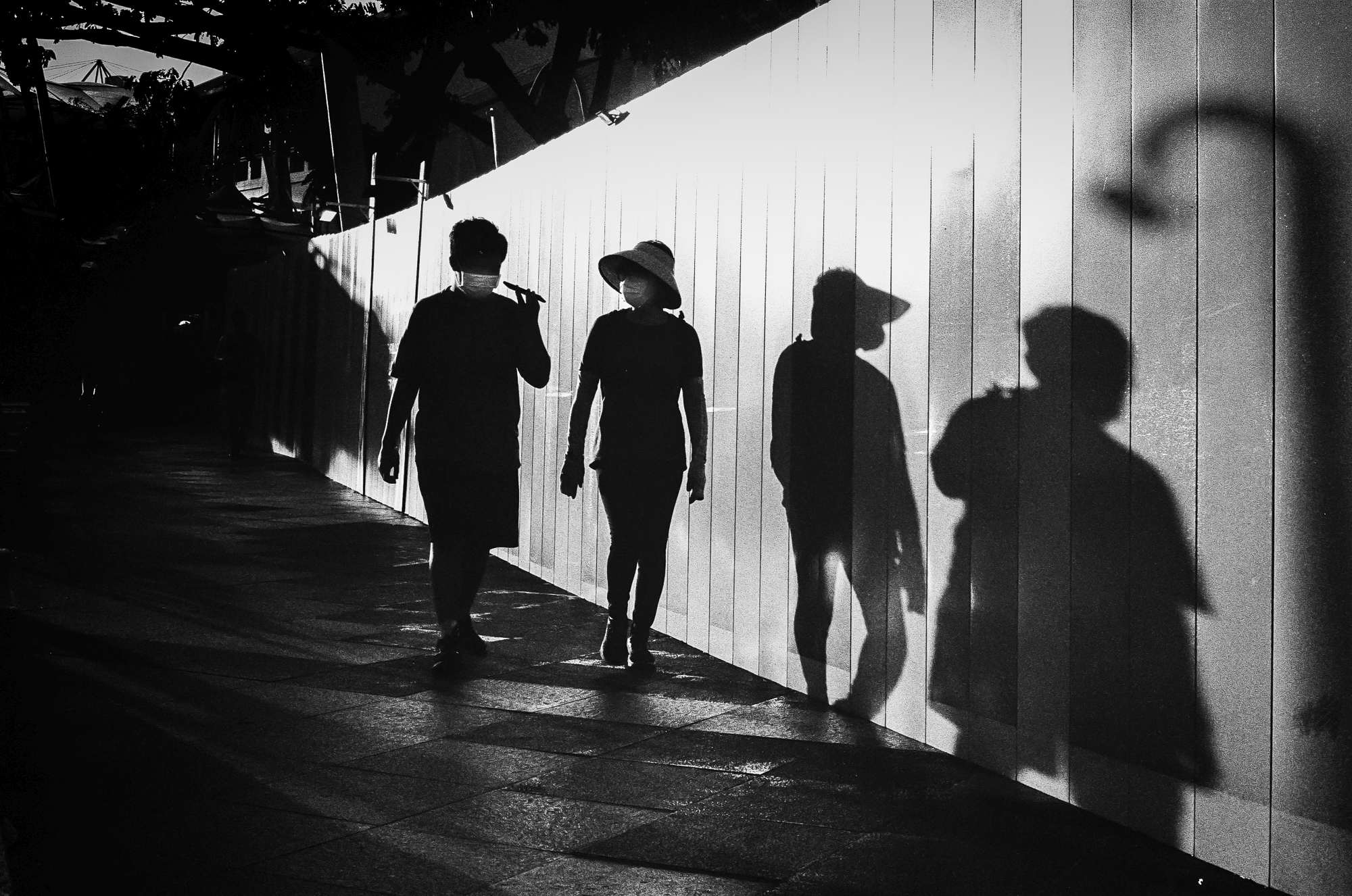 A silhouetted couple walking beside a wall illuminated with the fall-evening sunlight.