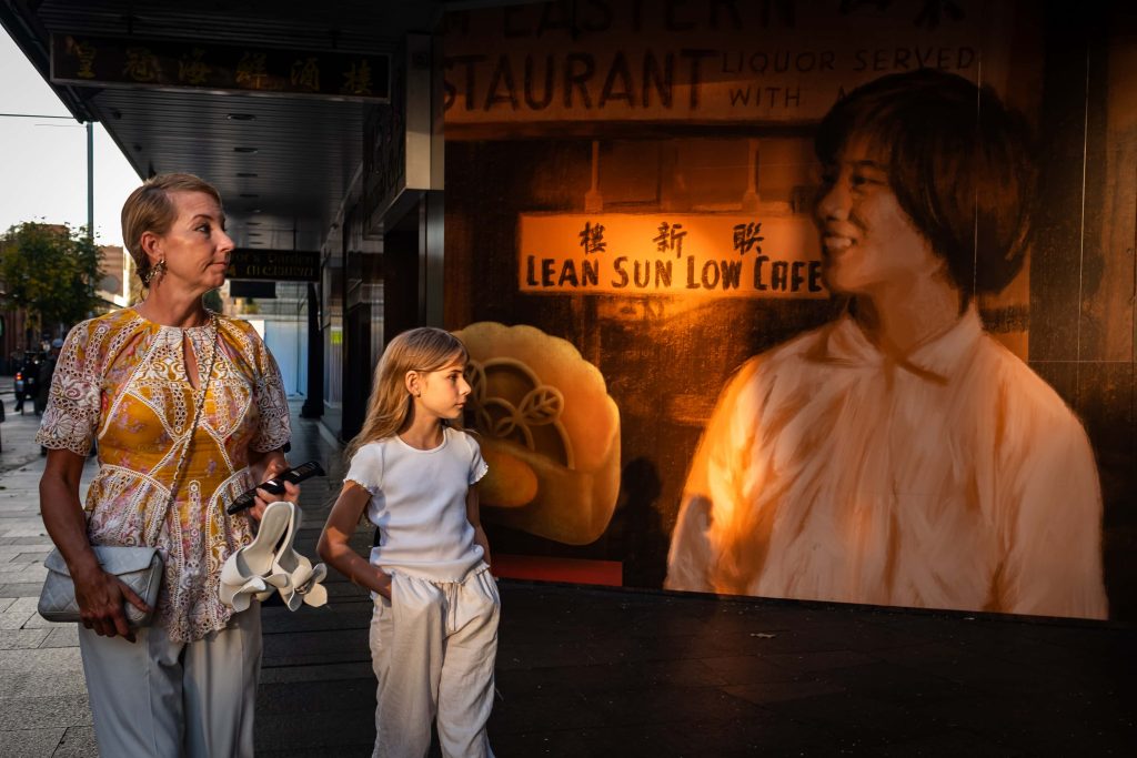 Two generations pause in the golden afternoon light, sharing a quiet moment framed by the vintage charm of the city streets.